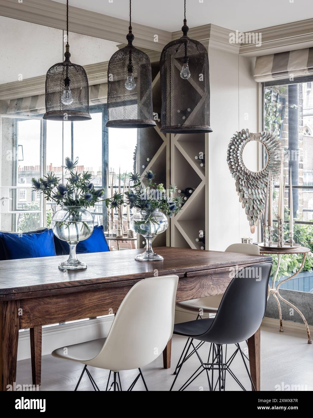 Suspensions au-dessus de la table avec des fleurs dans des vases en verre dans la salle à manger moderne élégante de l'appartement de Londres, Royaume-Uni Banque D'Images