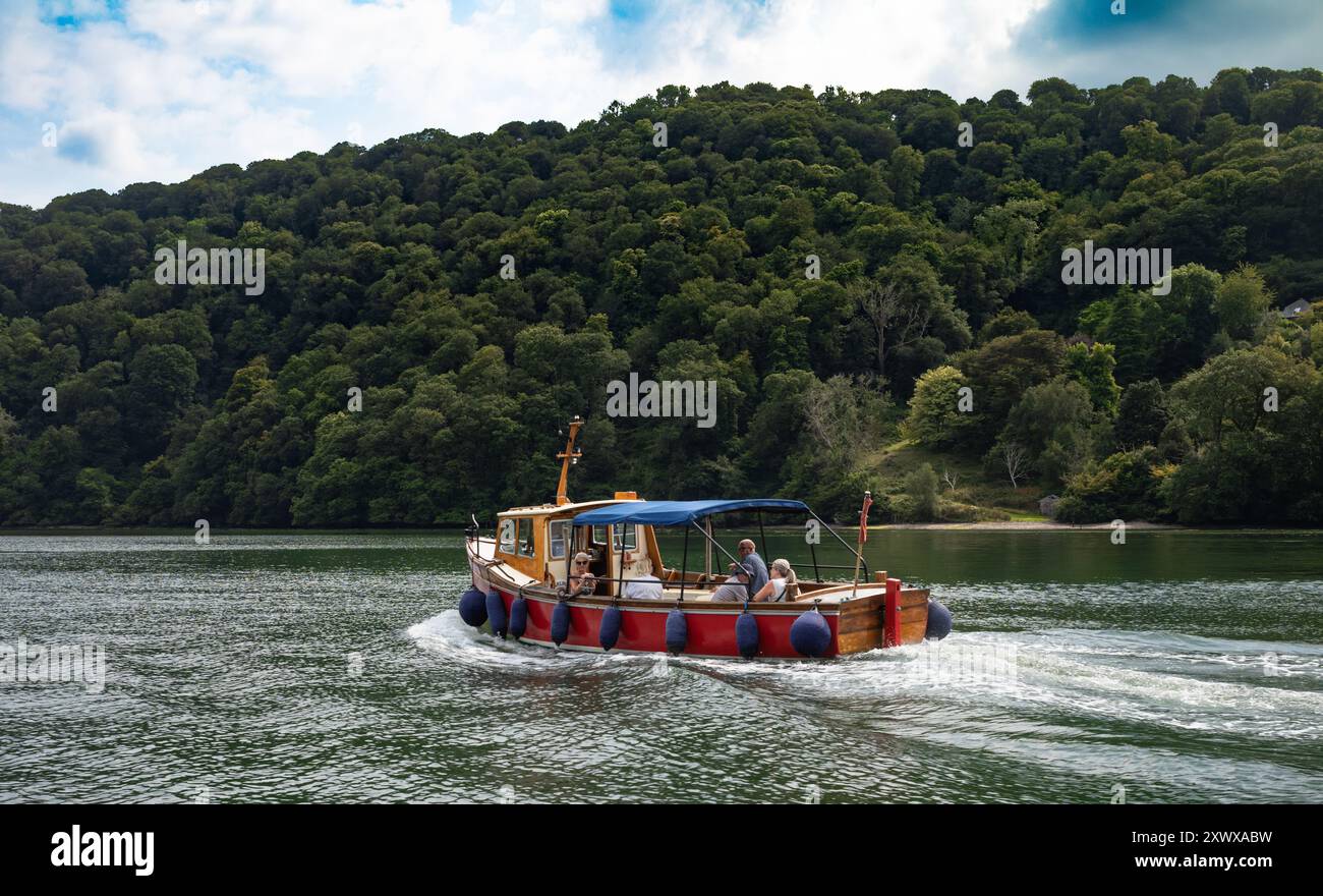 Les gens sont assis sur le ferry de Dittisham alors qu'il voyage vers le haut de l'estuaire de la rivière Dart près de Greenway, Devon, Angleterre, Royaume-Uni. Banque D'Images