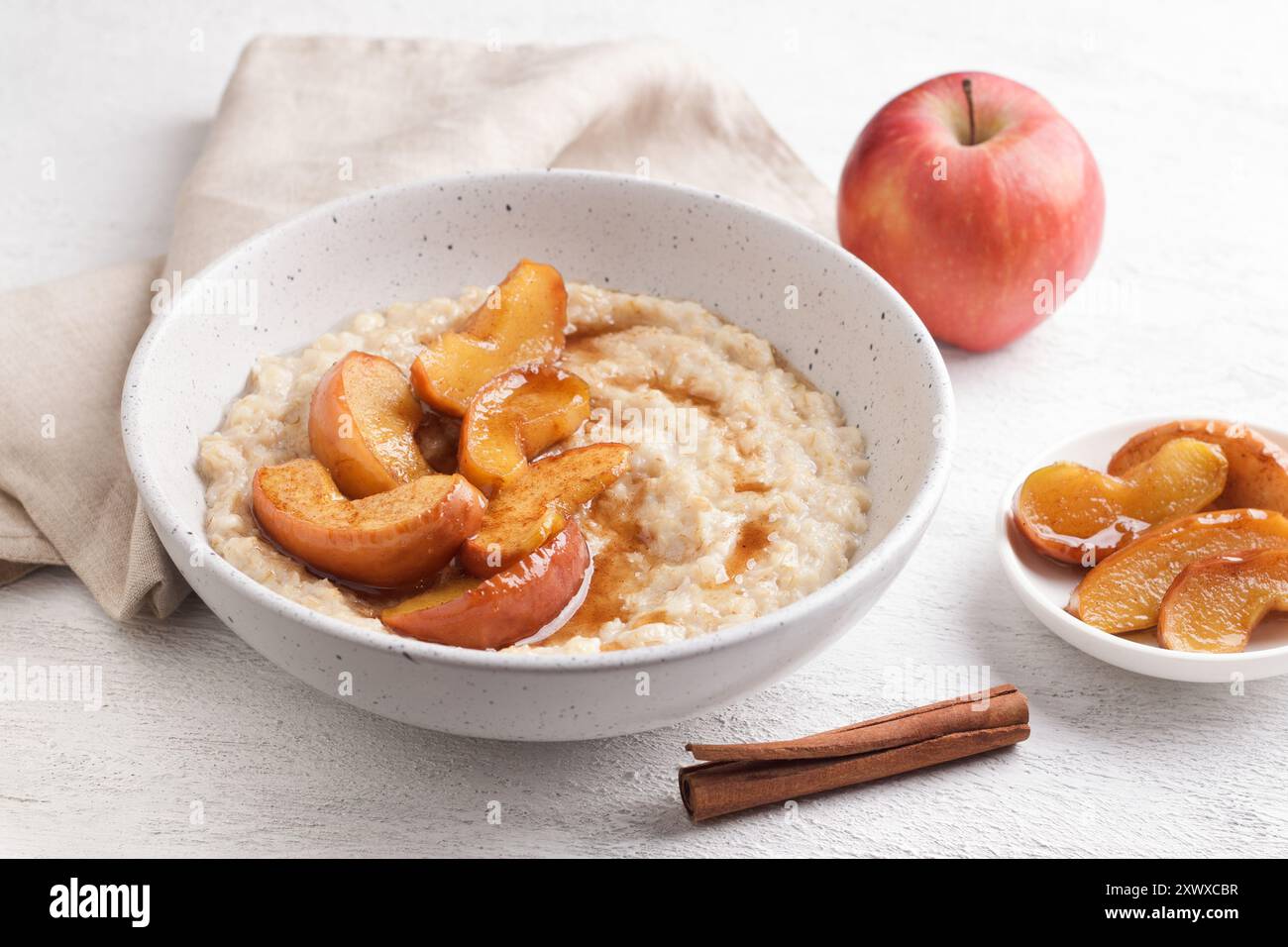 Bouillie d'avoine sucrée avec tranches de pomme cuites au four, cannelle et sauce caramel dans un bol gris sur un fond clair, vue de dessus. Délicieuse cuisine maison Banque D'Images