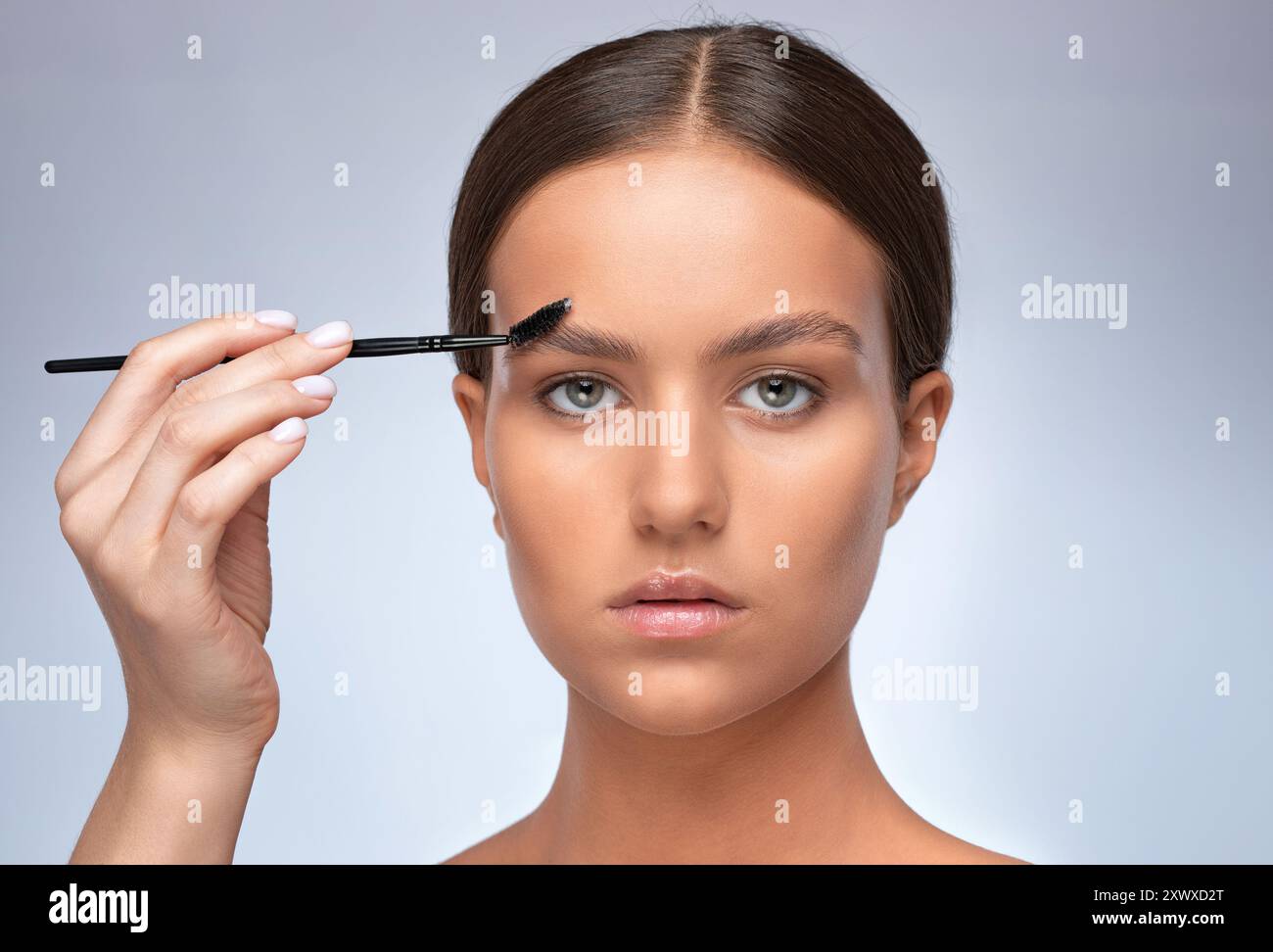 Maquilleuse peigne les sourcils avec un pinceau après la teinture dans un salon de beauté. Maquillage professionnel et soins de la peau de cosmétologie. Banque D'Images