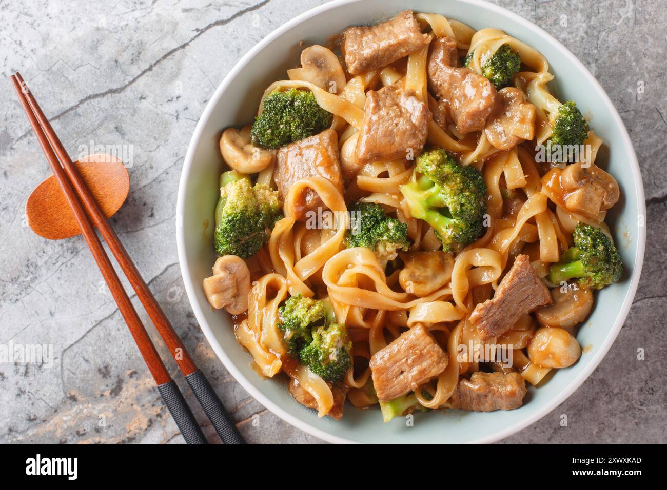 Bœuf de style asiatique, nouilles, champignons et brocoli dans un bol gros plan sur la table. Vue horizontale de dessus Banque D'Images