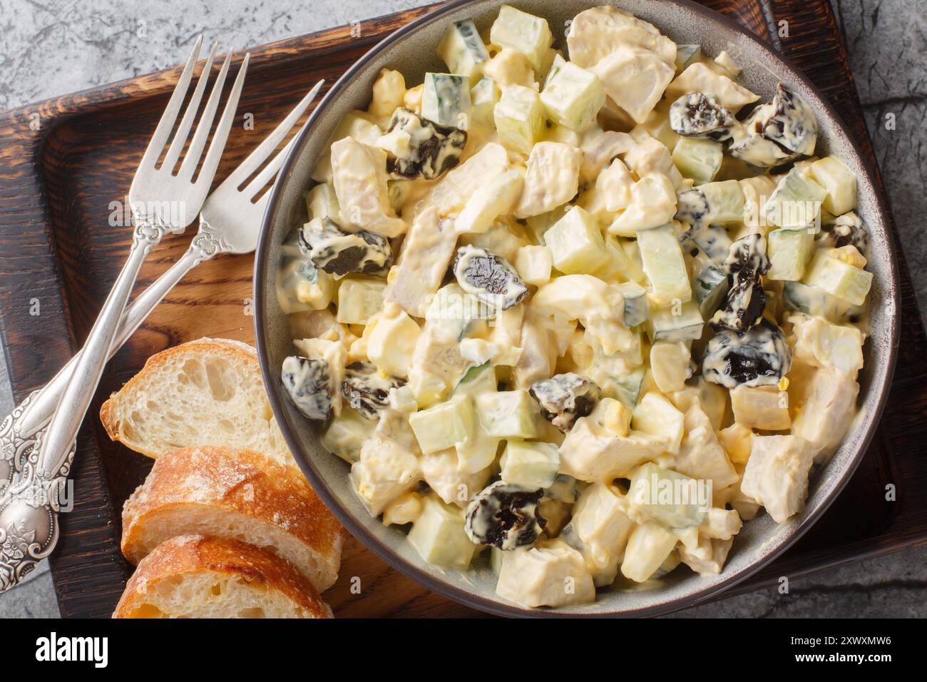 Délicieuse salade avec poulet, pruneaux, concombre et œufs gros plan dans un bol sur la table. Vue horizontale de dessus Banque D'Images