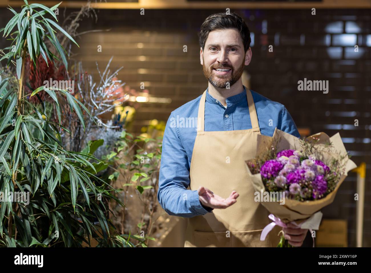 Fleuriste souriant dans le tablier tient un bouquet vibrant au magasin de fleurs, entouré de plantes luxuriantes. L'image capture l'essence de l'entreprise florale, la créativité et la passion pour les fleurs dans un environnement chaleureux et accueillant. Banque D'Images