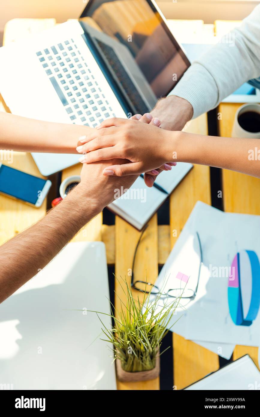 Esprit d'équipe. Vue de dessus des gens d'affaires tenant les mains accrochées sur le bureau en bois Banque D'Images