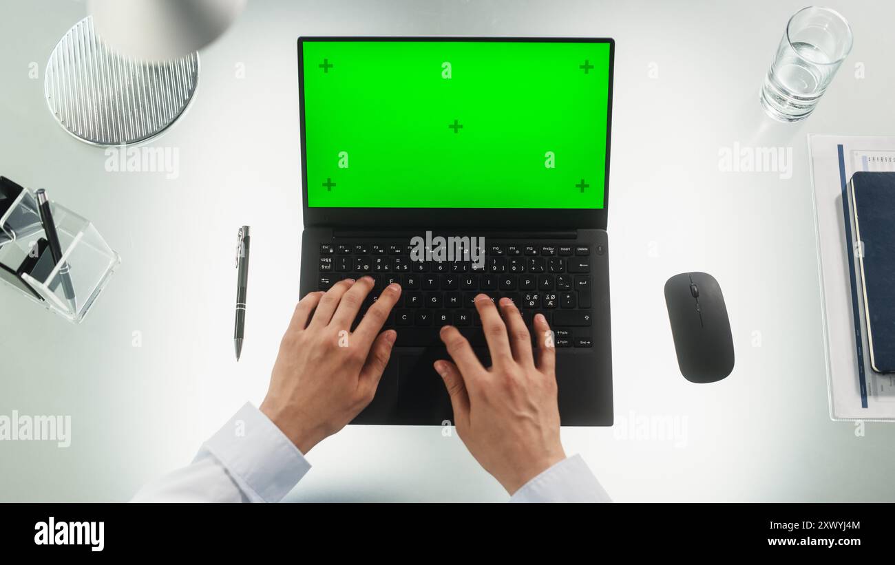 Travailleur de bureau anonyme tapant sur un ordinateur portable avec écran vert maquette Chromakey avec balises Motion Tracker. Manager correspondant avec les partenaires commerciaux par e-mail. Vue de haut en bas Banque D'Images