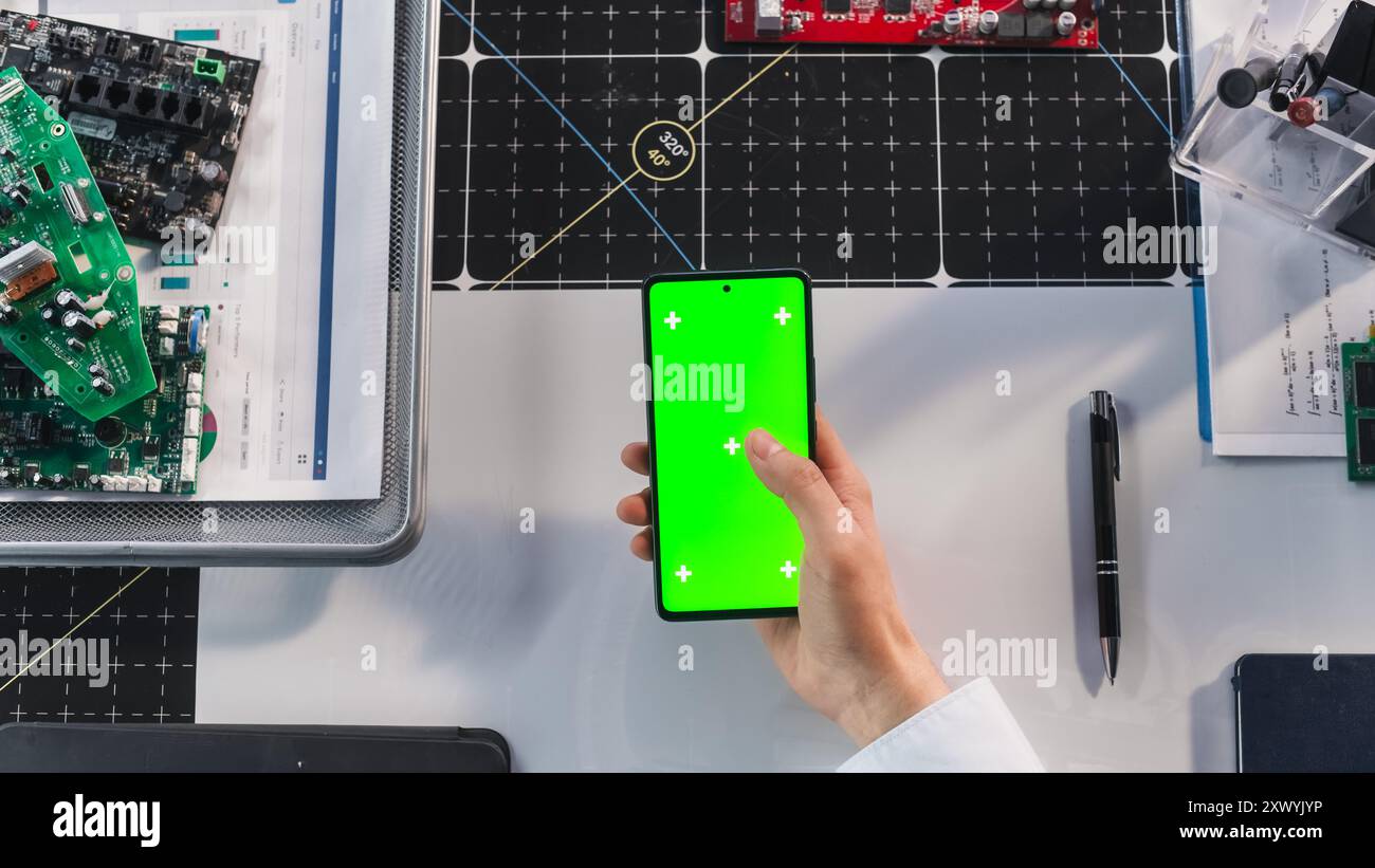 Business Manager défilement des applications sur smartphone avec écran vert Chromakey Mock Up Display dans un lieu de travail moderne. Modèle photo avec espace réservé isolé pour la démonstration de marketing numérique Banque D'Images