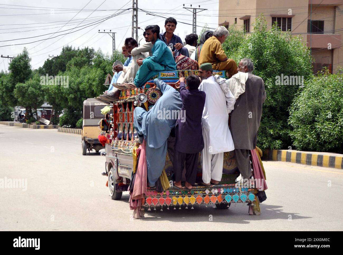 HYDERABAD, PAKISTAN 21/08/2024, , les passagers voyagent sur un véhicule surchargé qui peut causer un risque pour leur vie, en passant par une route violant les règles de circulation, ont besoin de l'attention des autorités, à Hyderabad le mercredi 21 août 2024. Banque D'Images