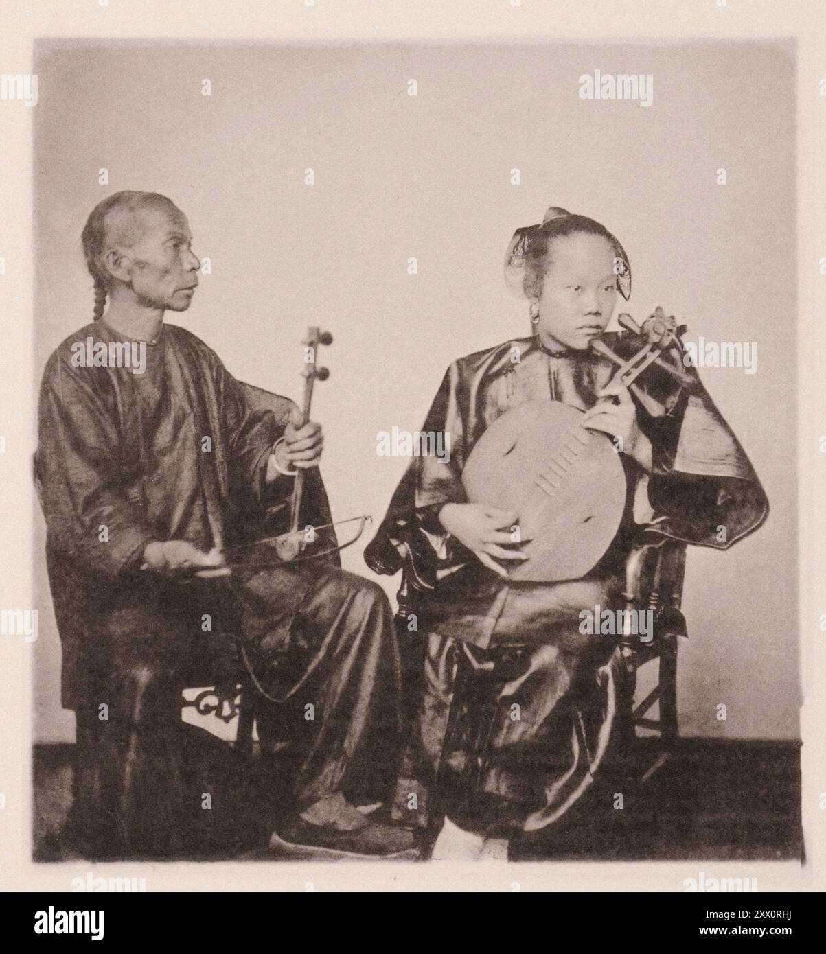 Photo vintage de musicains chinois, musicain aîné avec queue (coiffure). Illustrations de la Chine Qing, 1875 illustration représentent le violon et la guitare chinois, avec les interprètes, qui sont embauchés à des occasions festives. Les Chinois ont un certain nombre d'airs plaintifs et agréables qu'ils chantent ou interprètent sur leurs instruments à cordes et à vent. Banque D'Images