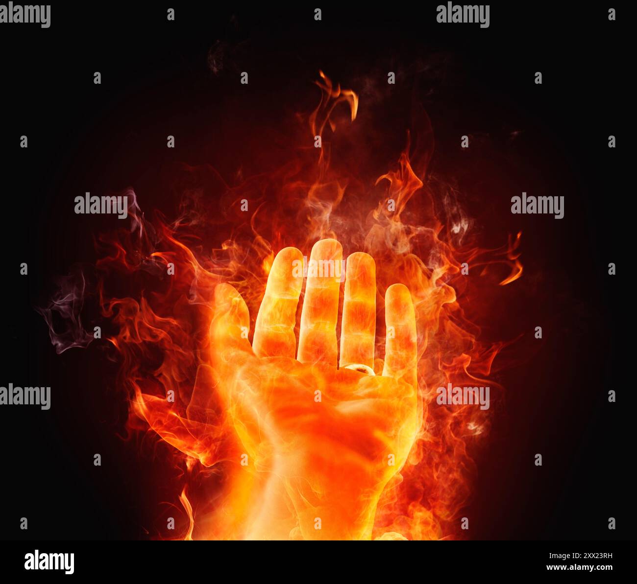 Main tendue conceptuelle sur le feu sur un fond noir Banque D'Images