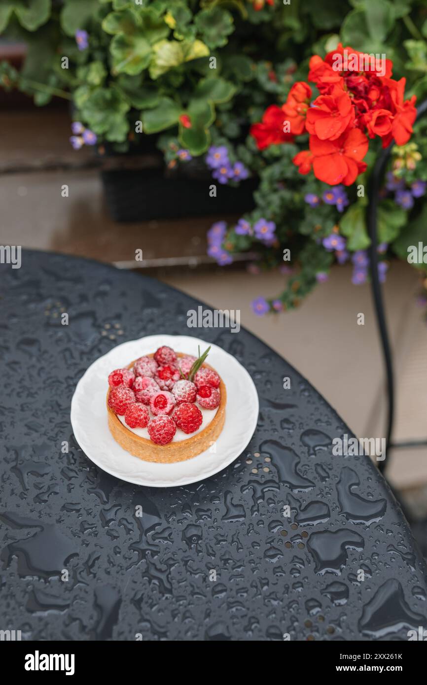Vue aérienne d'une tarte aux framboises individuelle sur une table humide dans un café en plein air Banque D'Images