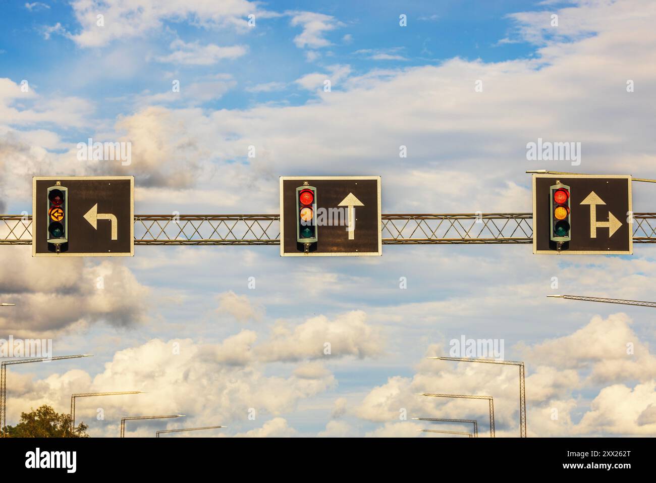 Belle vue sur les feux de circulation avec des panneaux de direction pour tourner à gauche, tout droit, et à droite ou tout droit sous le ciel nuageux. Banque D'Images