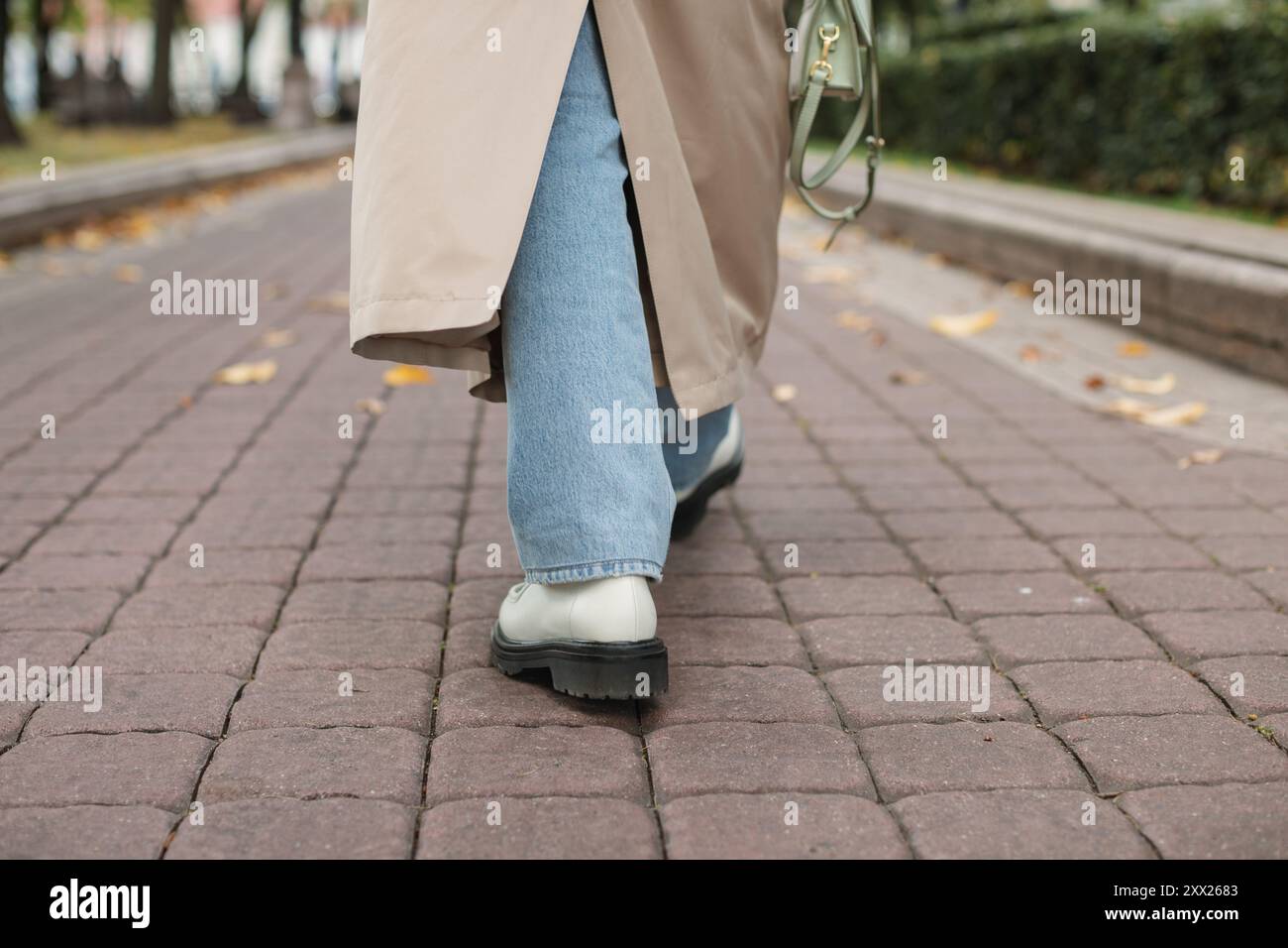 Vue arrière basse d'une femme dans un trench-coat marchant à travers le parc en automne, Biélorussie Banque D'Images