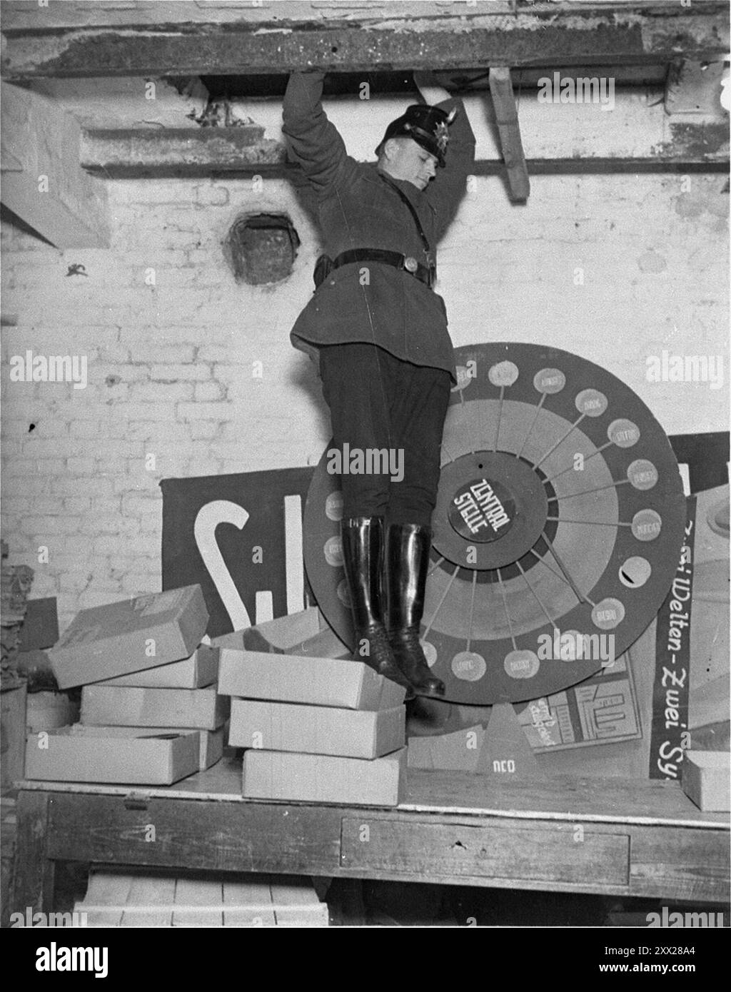 Un policier saute d'un trou dans le plafond qu'il a fouillé lors de la fermeture de la maison Karl-Liebknecht (siège du KPD), qui se trouvait sur la Buelowplatz à Berlin. Après que Hitler eut reçu le pouvoir, il se déplaça rapidement et efficacement pour le garder. Après l'incendie du Reichstag, les communistes ont été blâmés (qui a effectivement mis le feu est encore dans le doute). Après une campagne anti-comuniste frénétique, ils ont été déclarés illégaux, les membres ont été emprisonnés, leurs bureaux ont été saccagés et toute la littérature détruite. Avec l'opposition affective ainsi éliminée, les nazis remportèrent facilement les élections générales un mois plus tard. Banque D'Images
