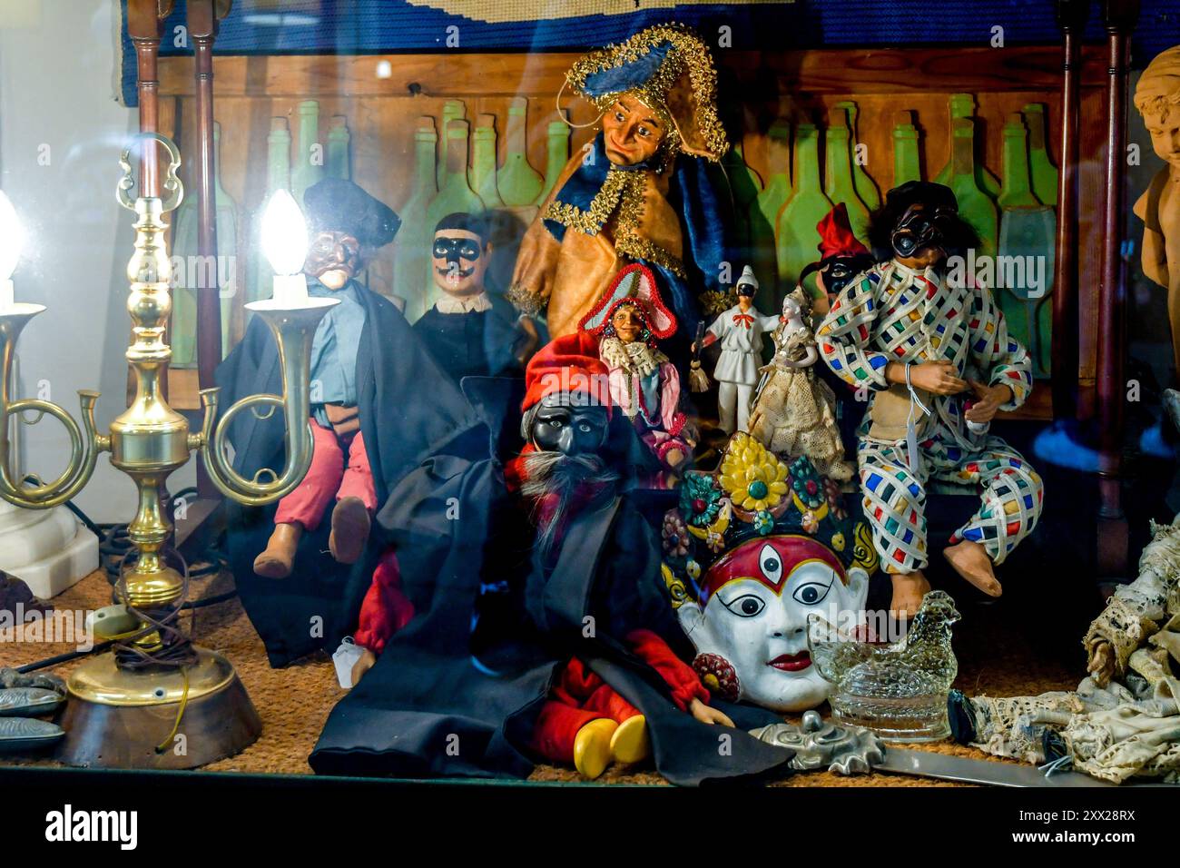Marionnettes anciennes dont les masques d'Arlequin, Pulcinella et Pantalone sur une table illuminée avec une lampe vintage, Florence, Toscane, Italie Banque D'Images
