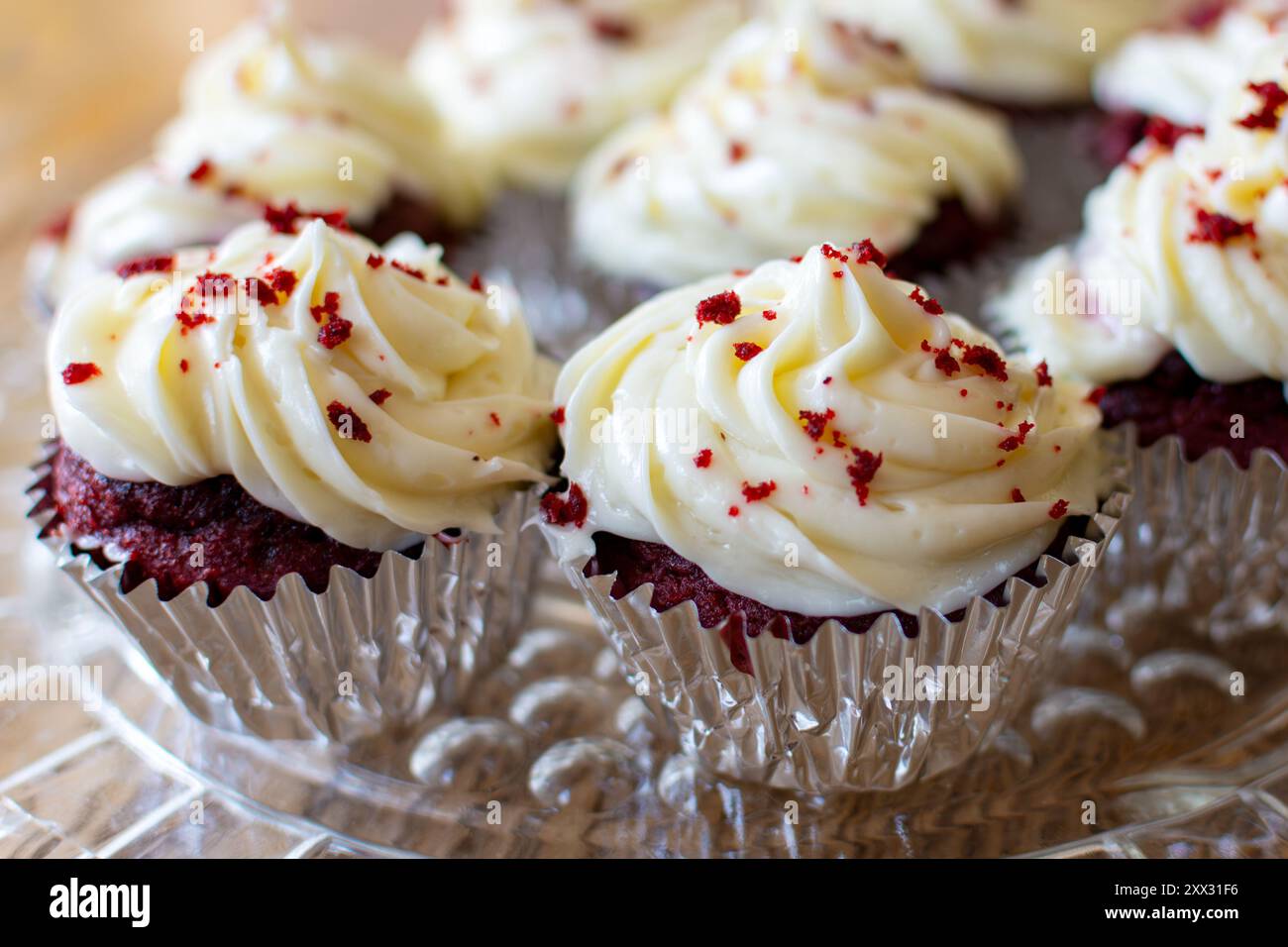 Vue rapprochée de cupcakes en velours rouge sur une plaque de verre transparente sur une table en bois. Banque D'Images