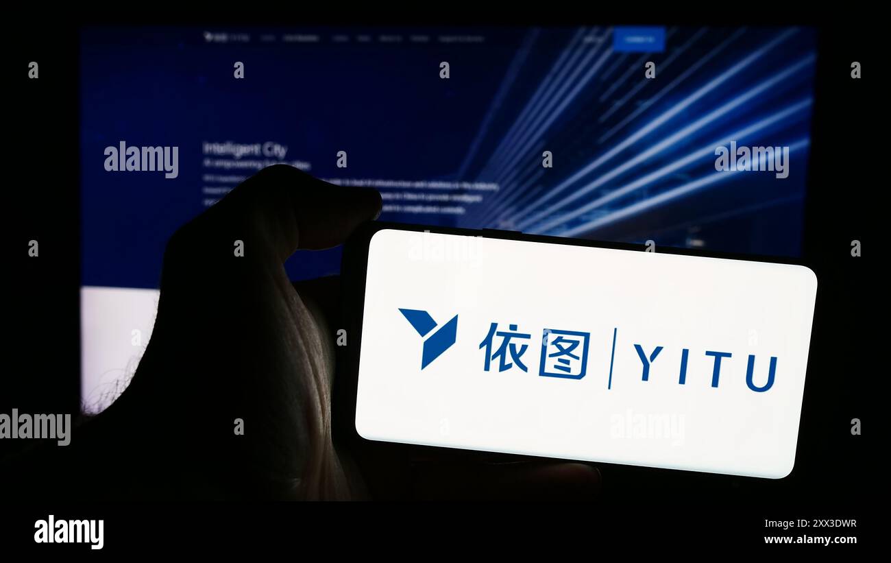 Personne tenant le téléphone portable avec le logo de la société chinoise ai Shanghai YITU Technology Co. Ltd en face de la page Web. Concentrez-vous sur l'affichage du téléphone. Banque D'Images
