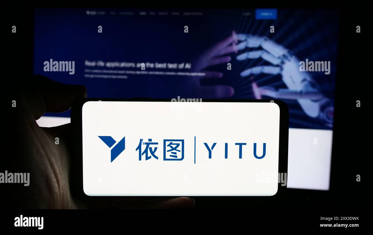 Personne tenant le téléphone portable avec le logo de la société chinoise ai Shanghai YITU Technology Co. Ltd devant la page Web d'affaires. Concentrez-vous sur l'affichage du téléphone. Banque D'Images