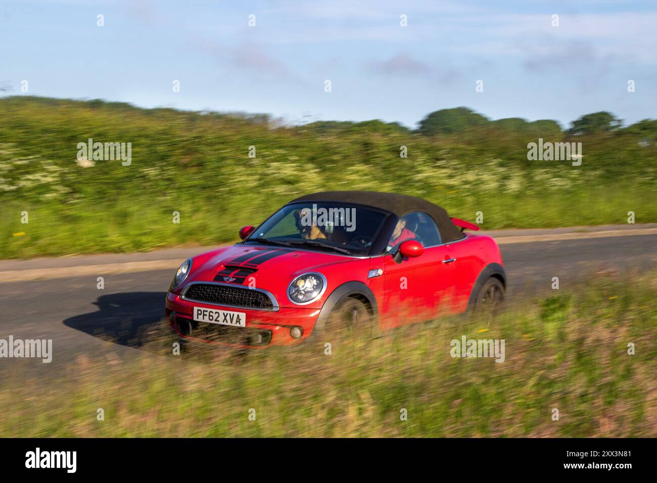 Chien alsacien assis sur le siège avant de LHD 2013 Red Mini Cooper SD ; automobile à Bolton, Royaume-Uni Banque D'Images