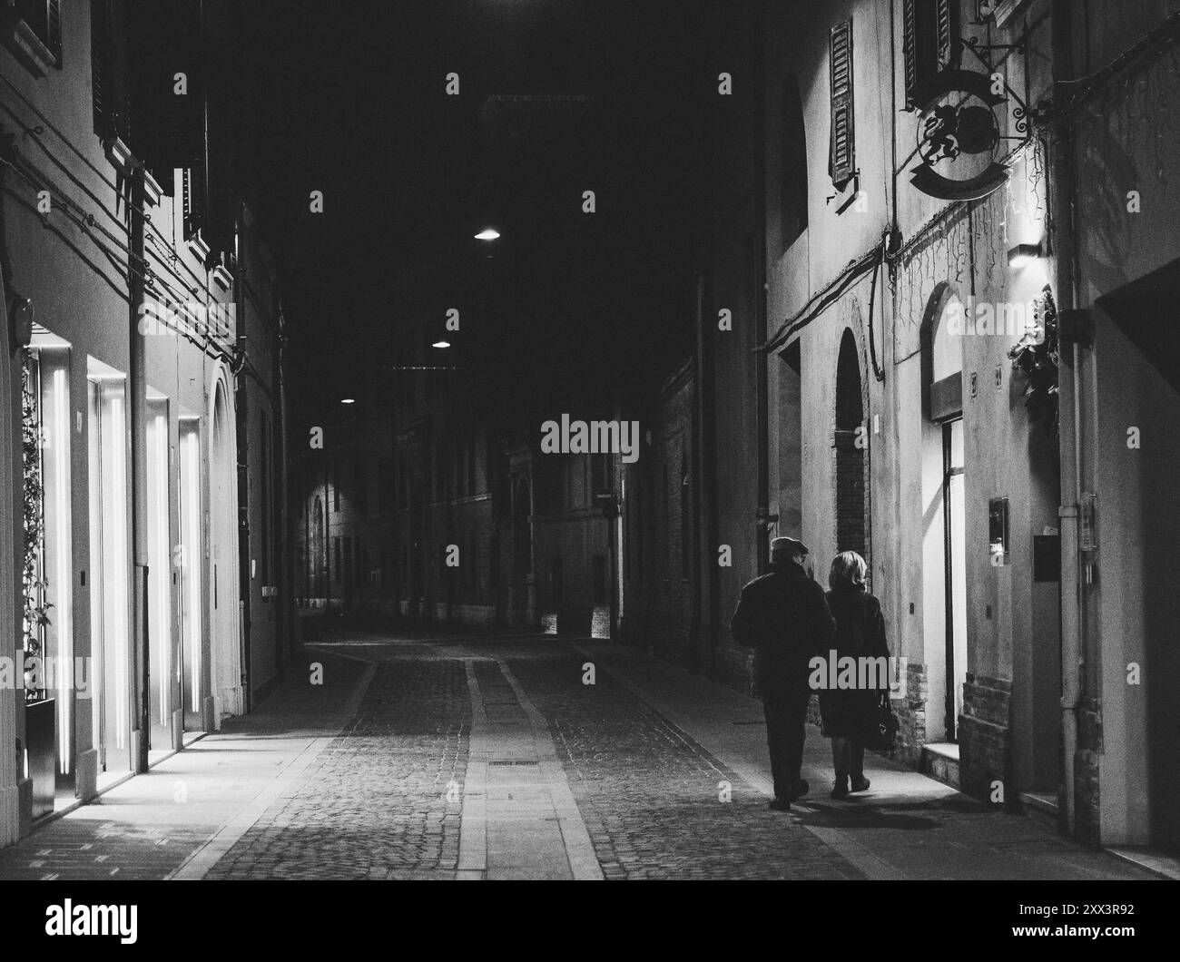 Un homme et une femme adultes marchent dans les rues d'une ville et s'arrêtent pour regarder une vitrine Banque D'Images