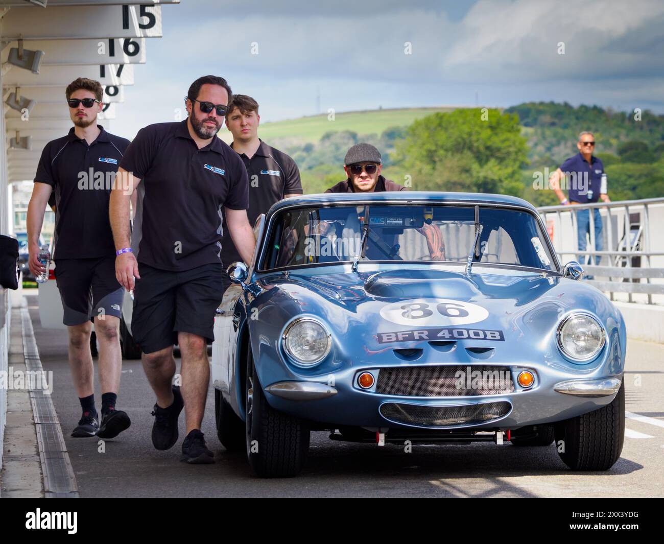 Mécaniciens poussant une voiture de course TVR dans la pitlane lors d'un jour d'essai Goodwood Revival 2024 Banque D'Images