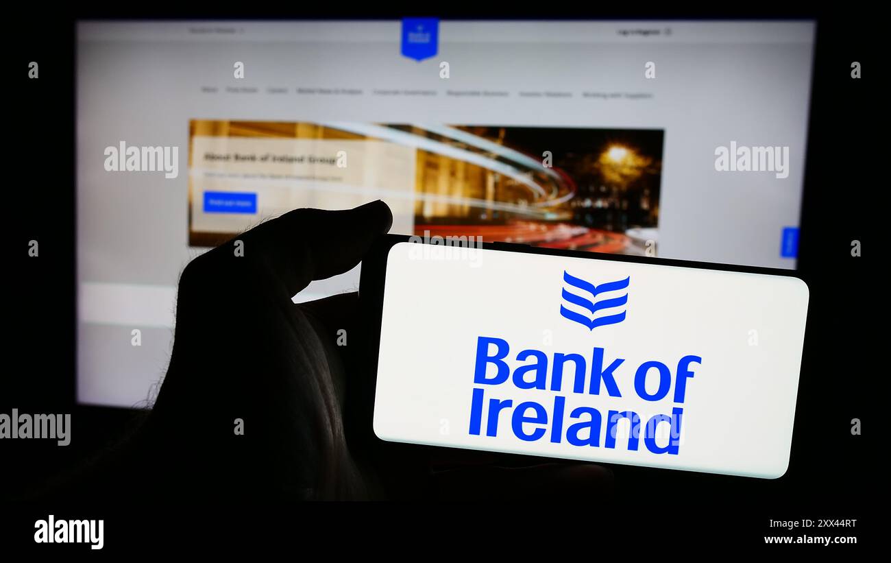 Personne tenant un smartphone avec le logo de la société financière irlandaise Bank of Ireland Group plc en face du site Web. Concentrez-vous sur l'affichage du téléphone. Banque D'Images