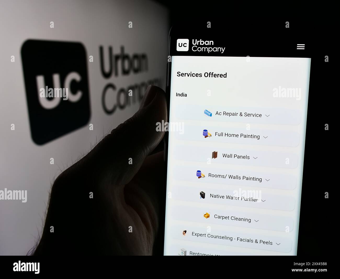 Personne tenant le téléphone portable avec la page Web de la société indienne de marché de services à domicile Urban Company avec logo. Concentrez-vous sur le centre de l'écran du téléphone. Banque D'Images