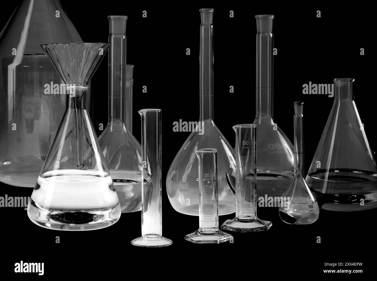 Variété de verrerie de laboratoire partiellement remplie dans le dos noir Banque D'Images