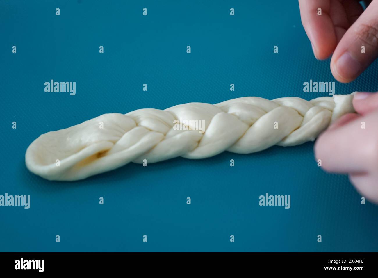 Main façonnant la pâte en la tressant. Procédé de fabrication de pain. Banque D'Images