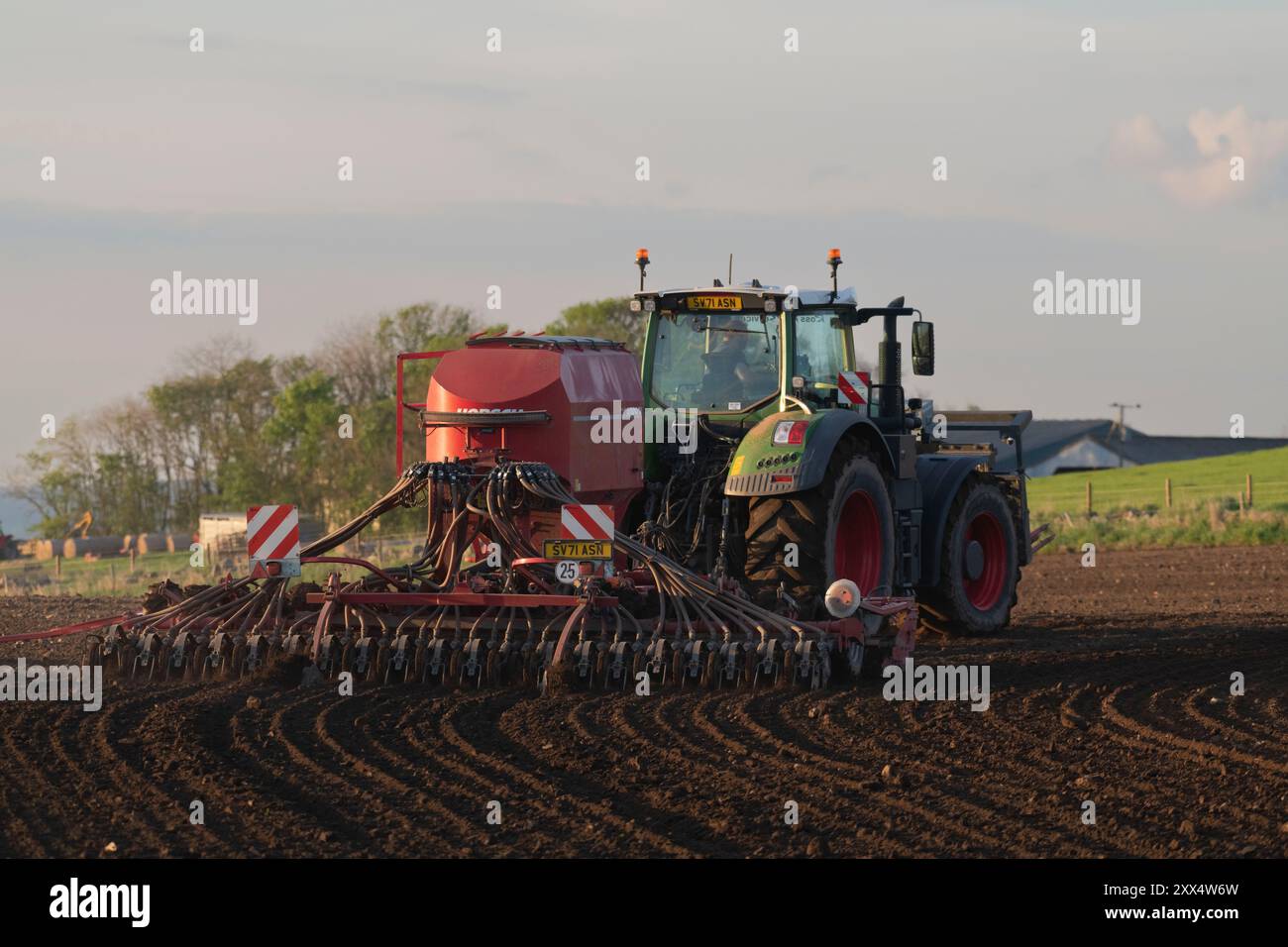 Tracteur Fendt vert équipé d'un semoir à disque rouge vu de l'arrière en plein soleil Banque D'Images