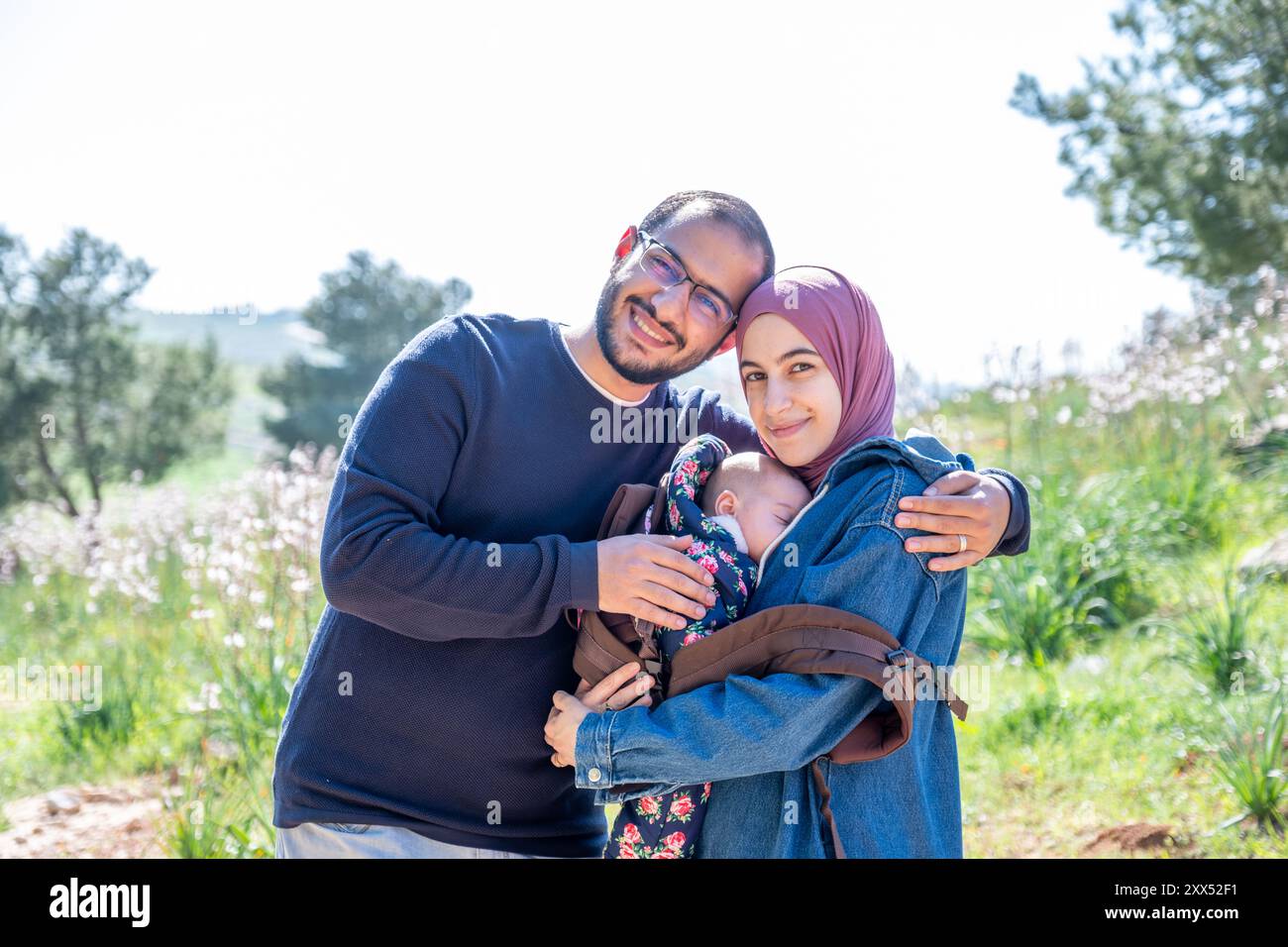 père, mère et bébé appréciant leur temps ensemble sur un pique-nique au milieu de champs verdoyants, créant de beaux souvenirs Banque D'Images