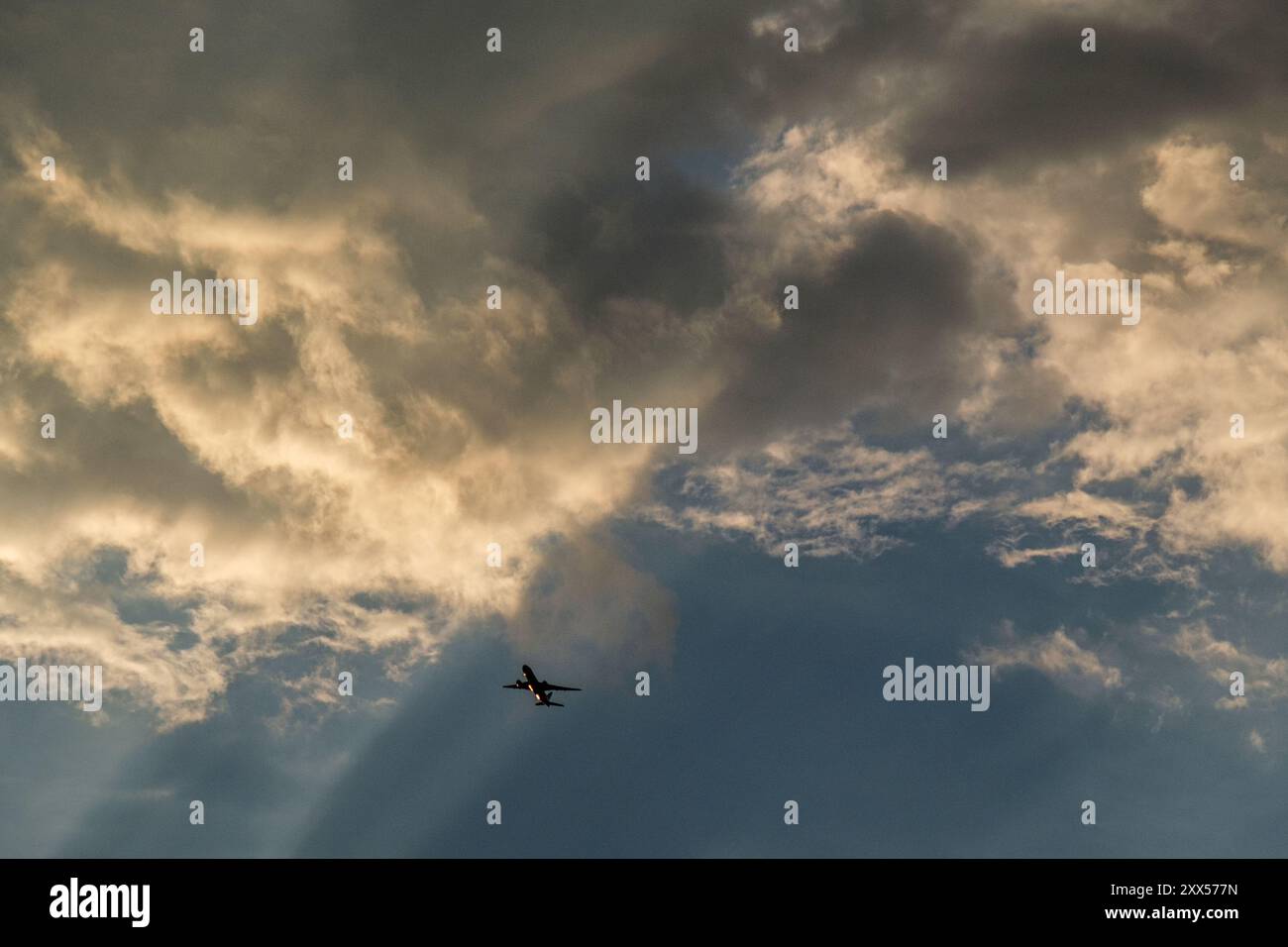 Aircaft grimpant dans les nuages de tempête dans la lumière du soleil du soir avec No People Banque D'Images