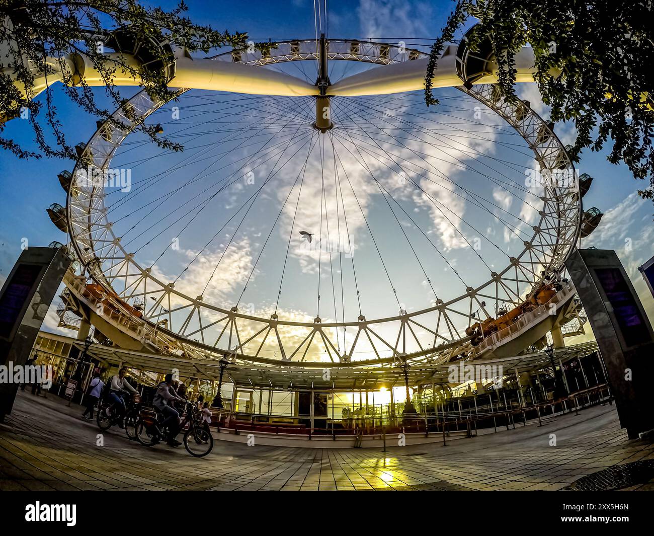 Capturé d'en bas, l'emblématique London Eye se distingue au coucher du soleil tandis qu'un oiseau survole son centre, près de la rive sud de la Tamise, à Londres. Banque D'Images