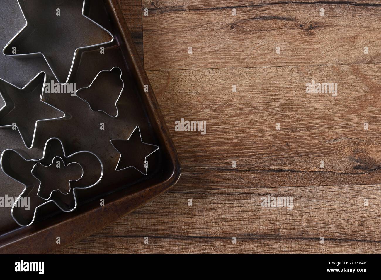 Gros plan vue aérienne d'un groupe d'emporte-pièces assortis sur une plaque à pâtisserie. Étoiles, hommes en pain d'épice et cloche sont représentés. Banque D'Images