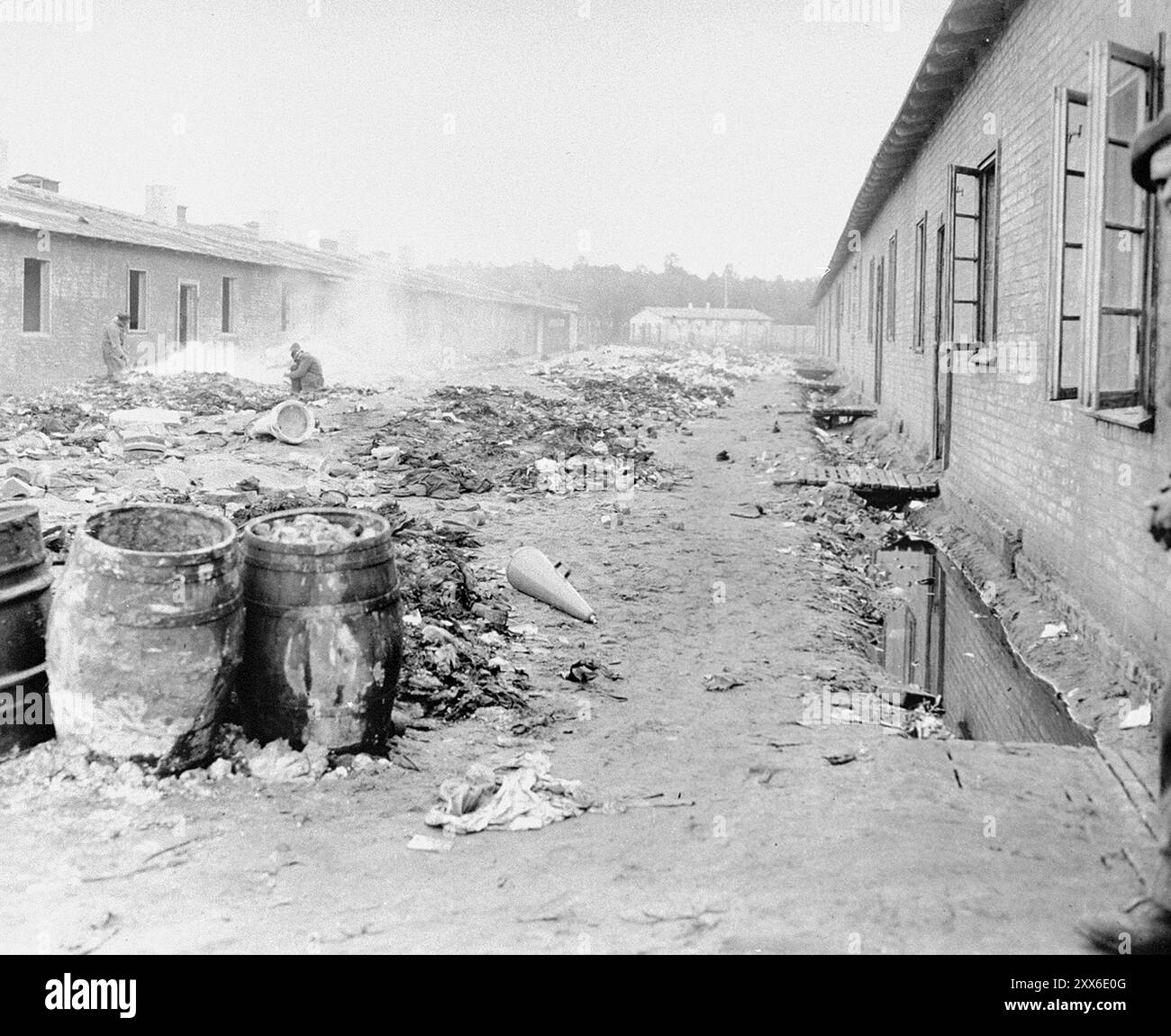 Une rue du camp de concentration de Bergen-Belsen, remplie de déchets. La photo est datée du 28 avril 1945, deux semaines après la libération du camp. La position du camp dans l'ouest de l'Allemagne signifiait que des milliers de personnes y furent envoyées alors que l'est tombait. 18000 personnes sont mortes rien qu'en mars 1945, et 10000 dans les deux semaines qui ont suivi la libération. Ils sont morts de maladie et de négligence plutôt que des abus systématiques observés ailleurs. Banque D'Images