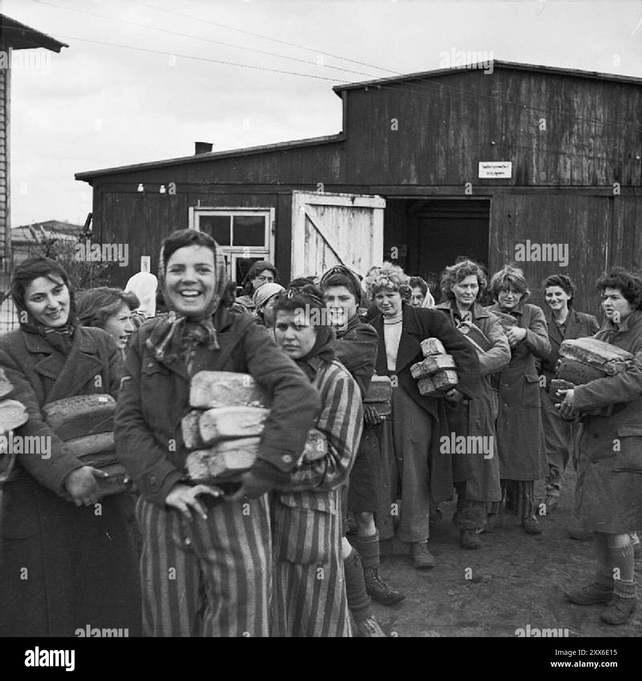 Heureuses survivantes du camp de concentration de Bergen-Belsen souriant après leur libération. Ils s'accrochent tous des pains. La position du camp dans l'ouest de l'Allemagne signifiait que des milliers de personnes y furent envoyées alors que l'est tombait. 18000 personnes sont mortes rien qu'en mars 1945, et 10000 dans les deux semaines qui ont suivi la libération. Ils sont morts de maladie et de négligence plutôt que des abus systématiques observés ailleurs. Banque D'Images