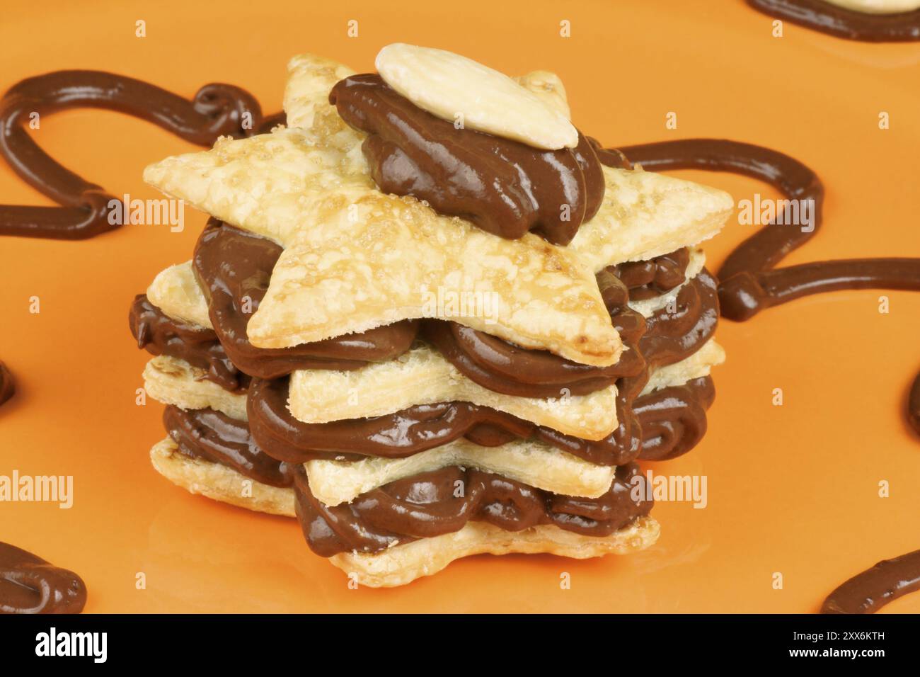 Crème au chocolat en forme d'étoile et millefeuille d'amande sur une assiette orange. Mise au point sélective Banque D'Images