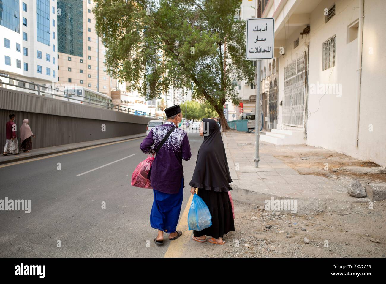 La Mecque, Arabie Saoudite - 12 juin 2024 : un couple de pèlerins indonésiens du Hajj et de la Umrah marchant après avoir acheté des cadeaux à Makkah, Arabie Saoudite. Hajj 2024. Banque D'Images