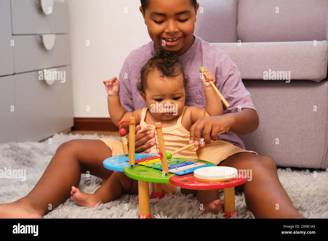 Frère enseignant à bébé soeur comment jouer de la musique sur xylophone Banque D'Images