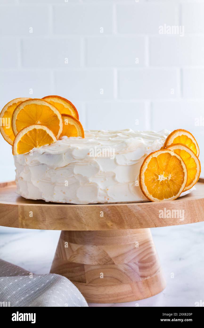 Gâteau blanc à l'orange givré avec des tranches d'orange séchées sur un support en bois Banque D'Images