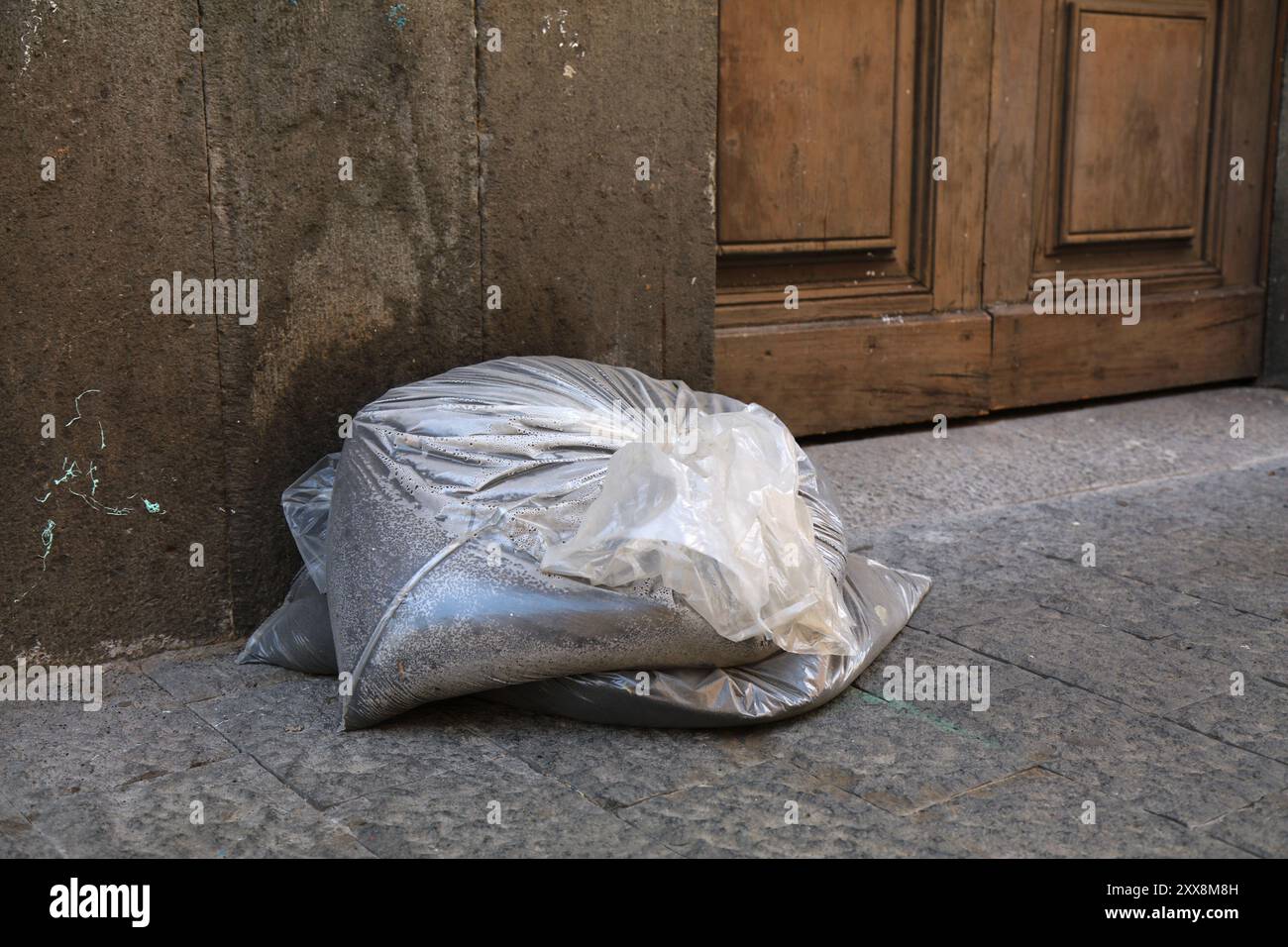 Poussière volcanique dans la rue de Giarre, ville métropolitaine de Catane en Sicile, Italie. Cendres du volcan Etna dans le sac en attente de la collecte des ordures servies Banque D'Images