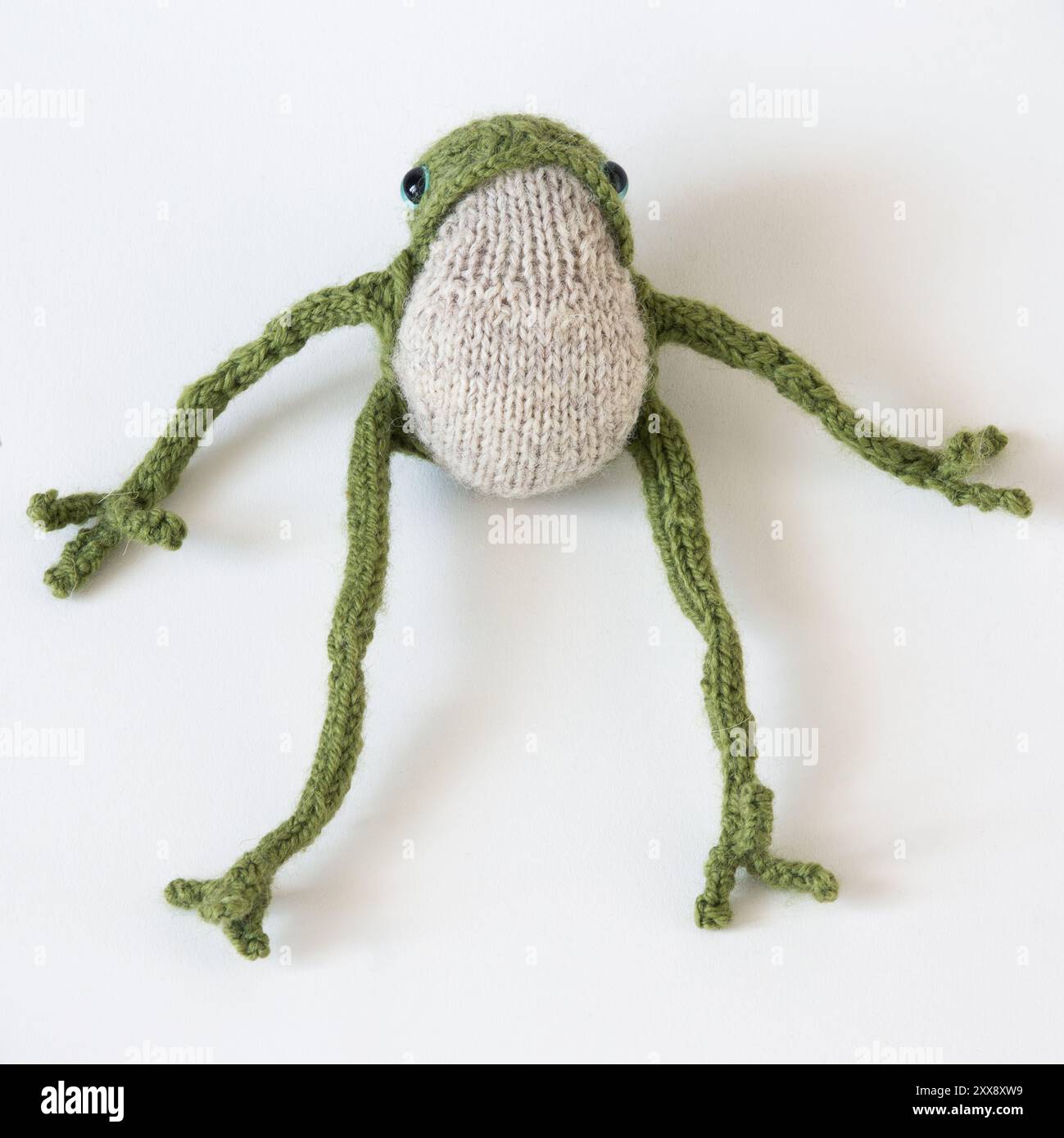 Grenouille verte tricotée avec de longues pattes sur un fond blanc Banque D'Images