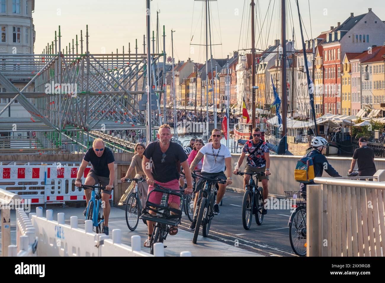 Cyclistes traversant un pont à Nyhavn à Copenhague, Danemark, un jour d'été. Banque D'Images