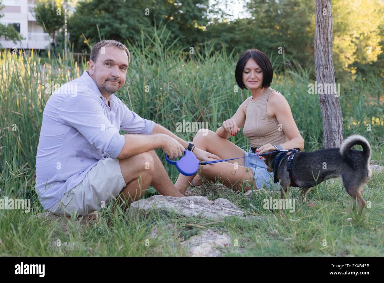 Un couple souriant heureux marchant, embrassant et embrassant dans le parc au coucher du soleil de la fin de l'été Banque D'Images