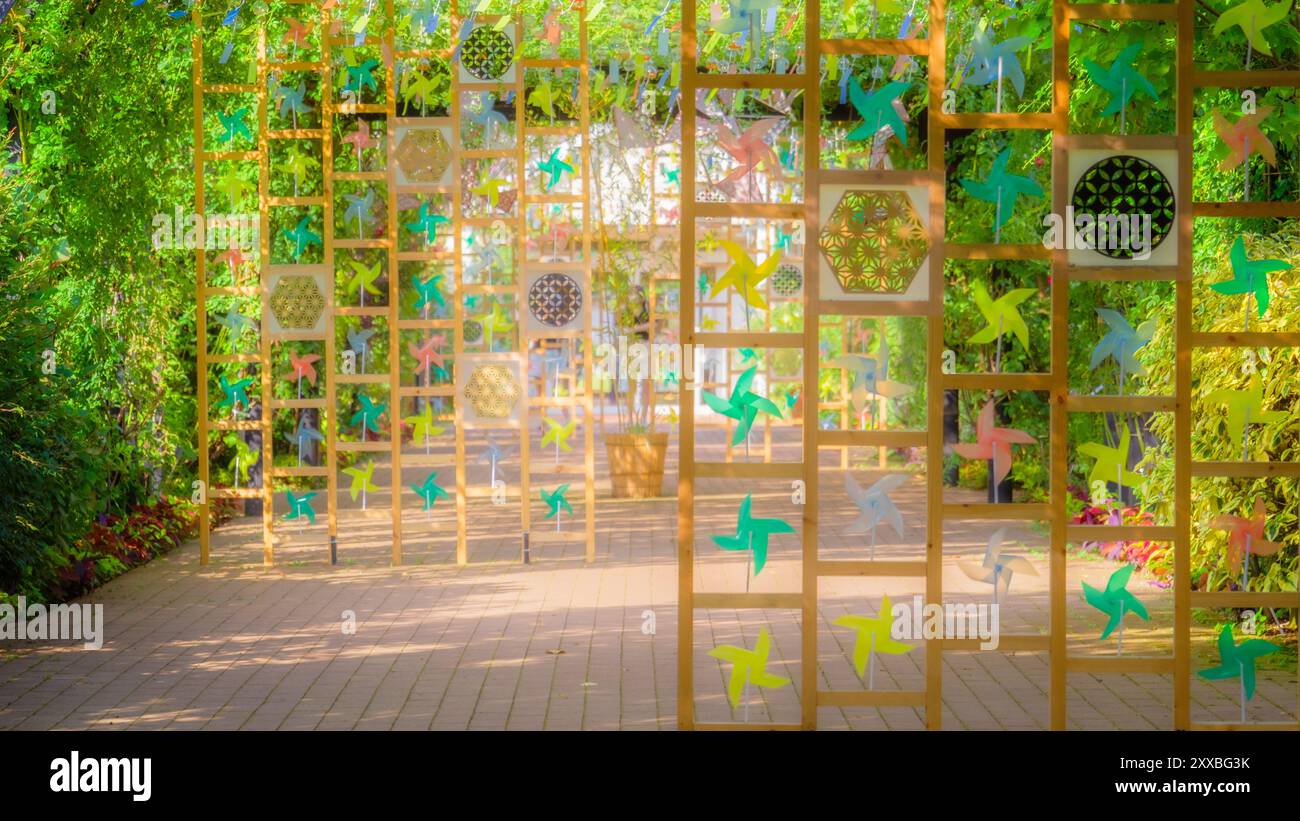 Promenez-vous dans le vibrant "Rose tunnel" pendant le Festival d'été, où des carillons de vent colorés et des moulins à vent ludiques créent des visuels apaisants Banque D'Images