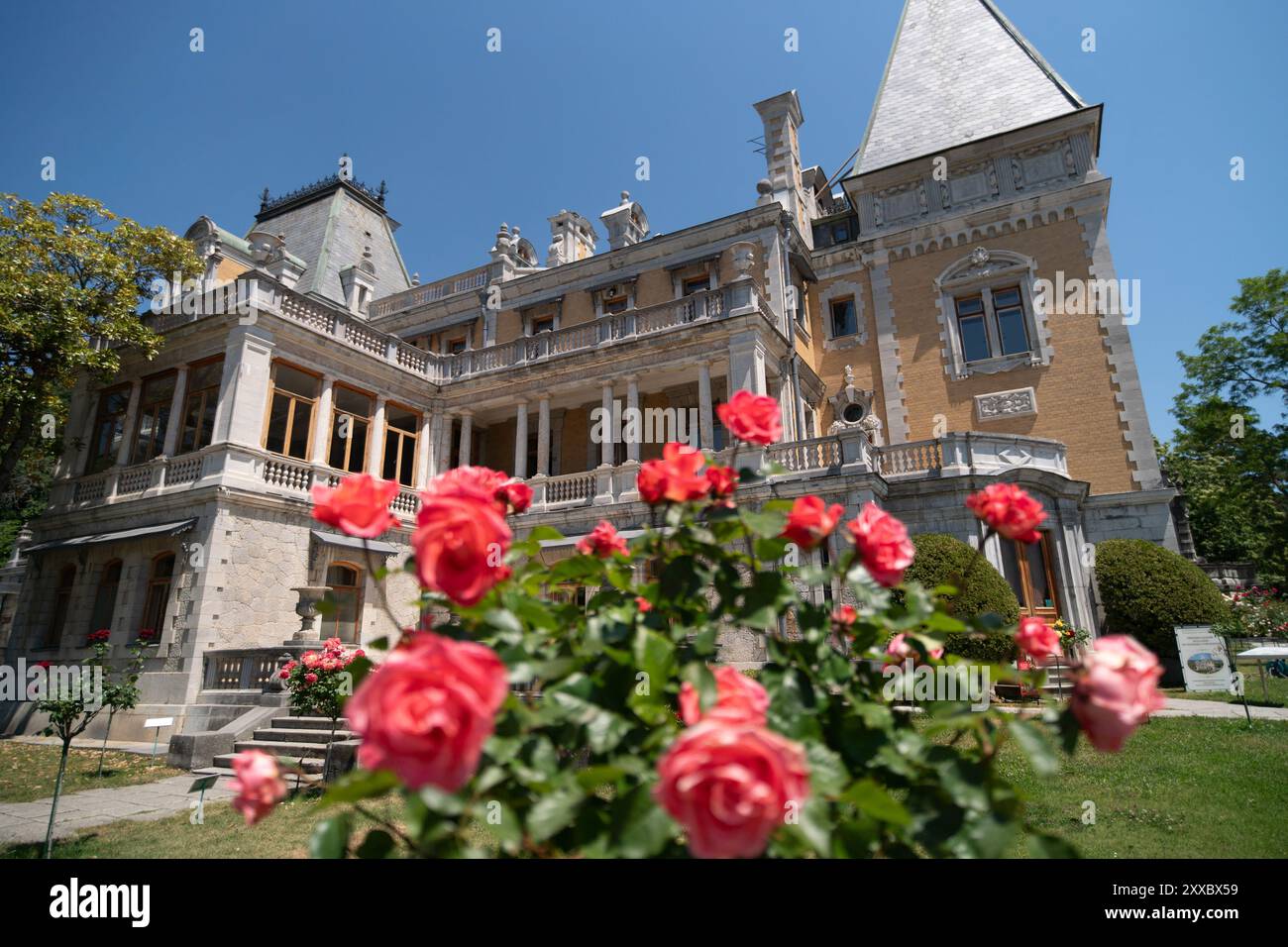 Un grand bâtiment avec beaucoup de fenêtres et un balcon. Le balcon est recouvert de roses rouges. Banque D'Images