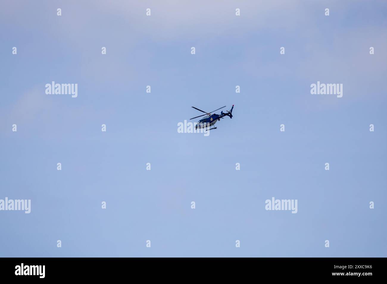 Un hélicoptère de la police suédoise volant dans un ciel bleu clair, présentant ses rotors et son design élégant. Banque D'Images