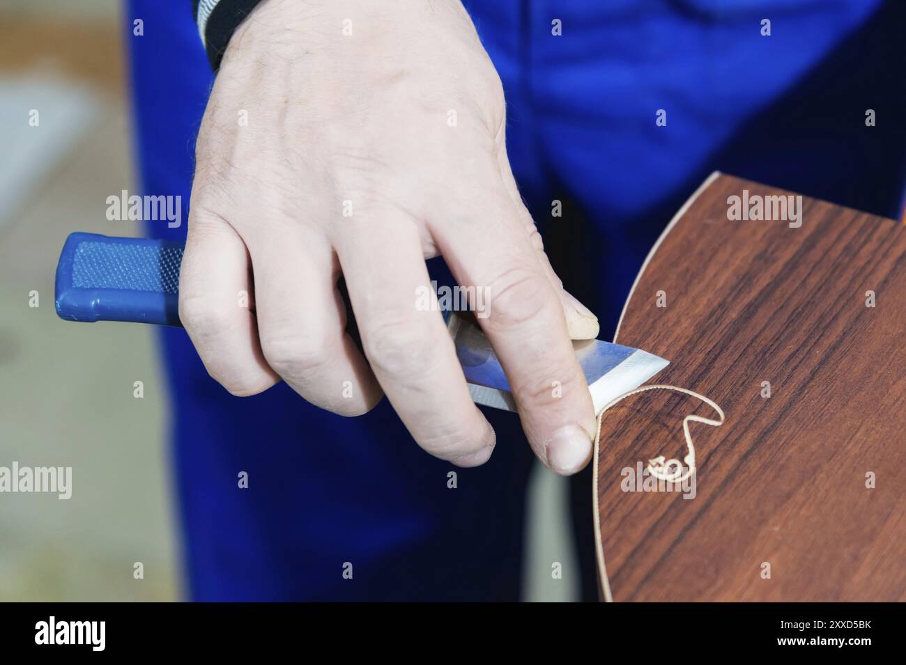 Un menuisier professionnel traite les bords en plastique du comptoir avec une coupe à couteau. Le concept de production de meubles Banque D'Images