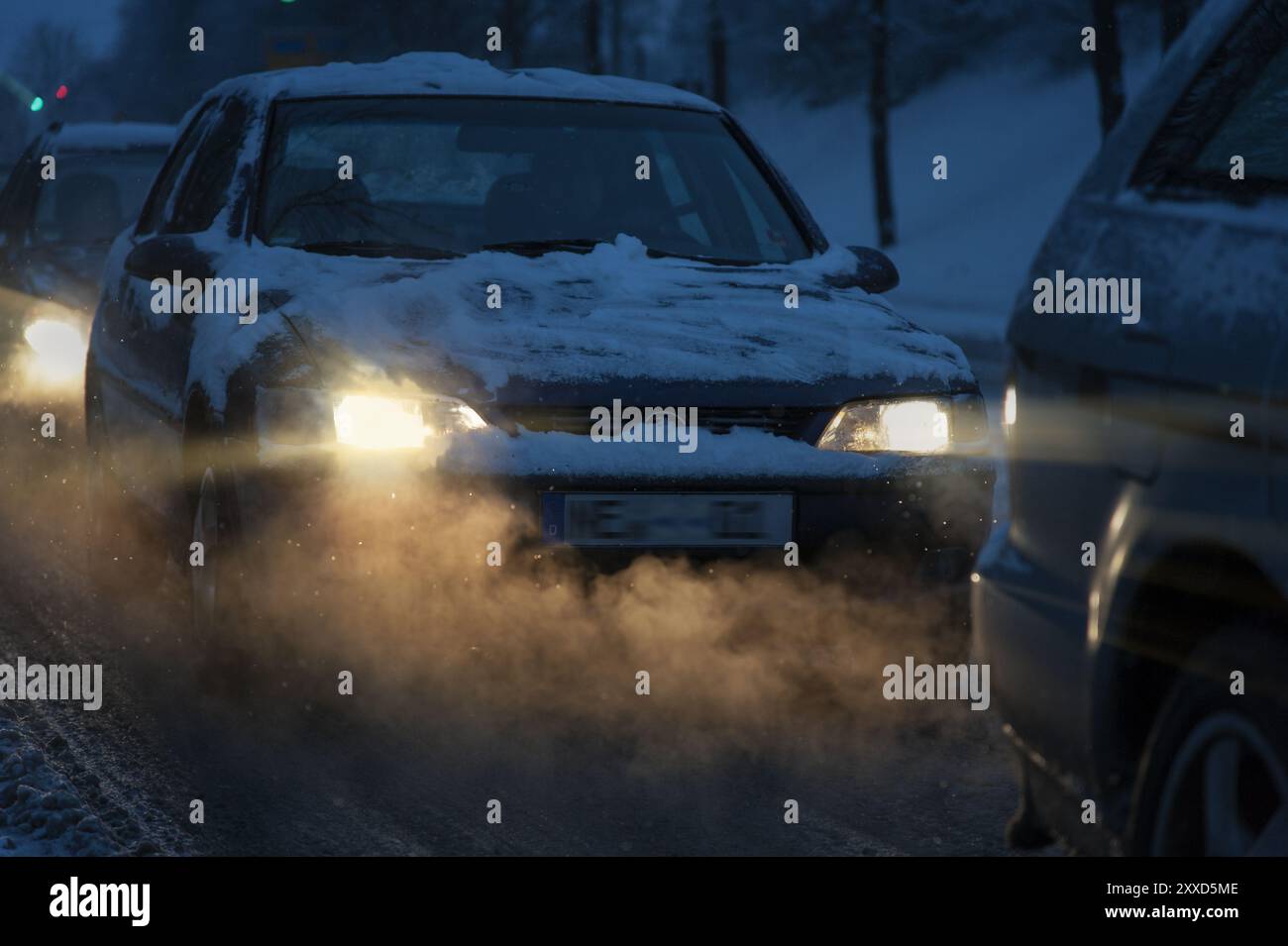 Gaz d'échappement d'une voiture stationnaire dans les phares de la voiture derrière Banque D'Images