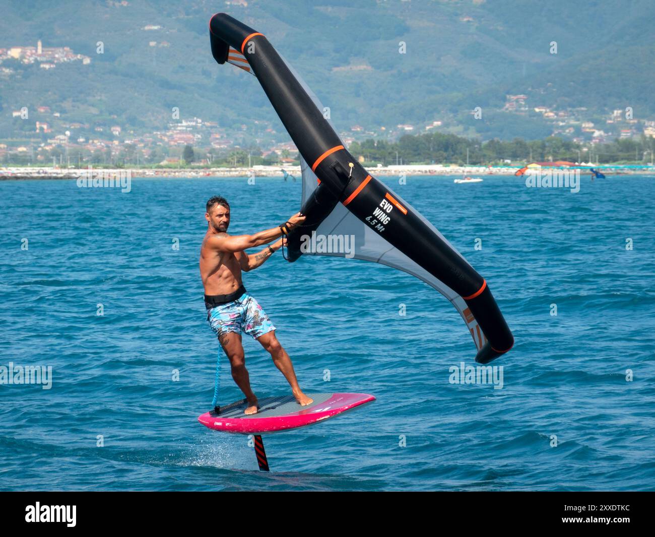 Fiumaretta di Ameglia, Italie - 22 août 2024 : L'homme pratique le fleuret dans la mer ligure. Wing foil est un sport nautique dynamique combinant le surf et le K. Banque D'Images