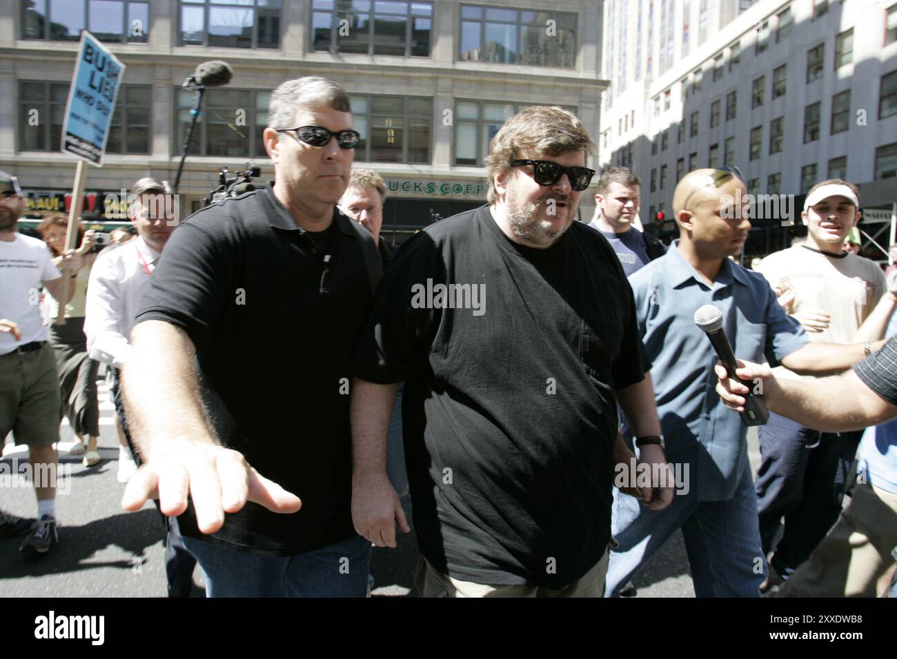 Des dizaines de milliers de manifestants défilent dans les rues de Manhattan pour protester contre la Convention républicaine du GOP. Michael Moore est escorté en sécurité par des bodygouards. Banque D'Images